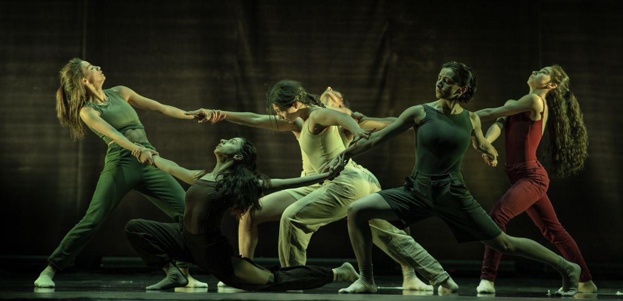 Contemporary dancers performing a dramatic routine with synchronization and movement on stage.