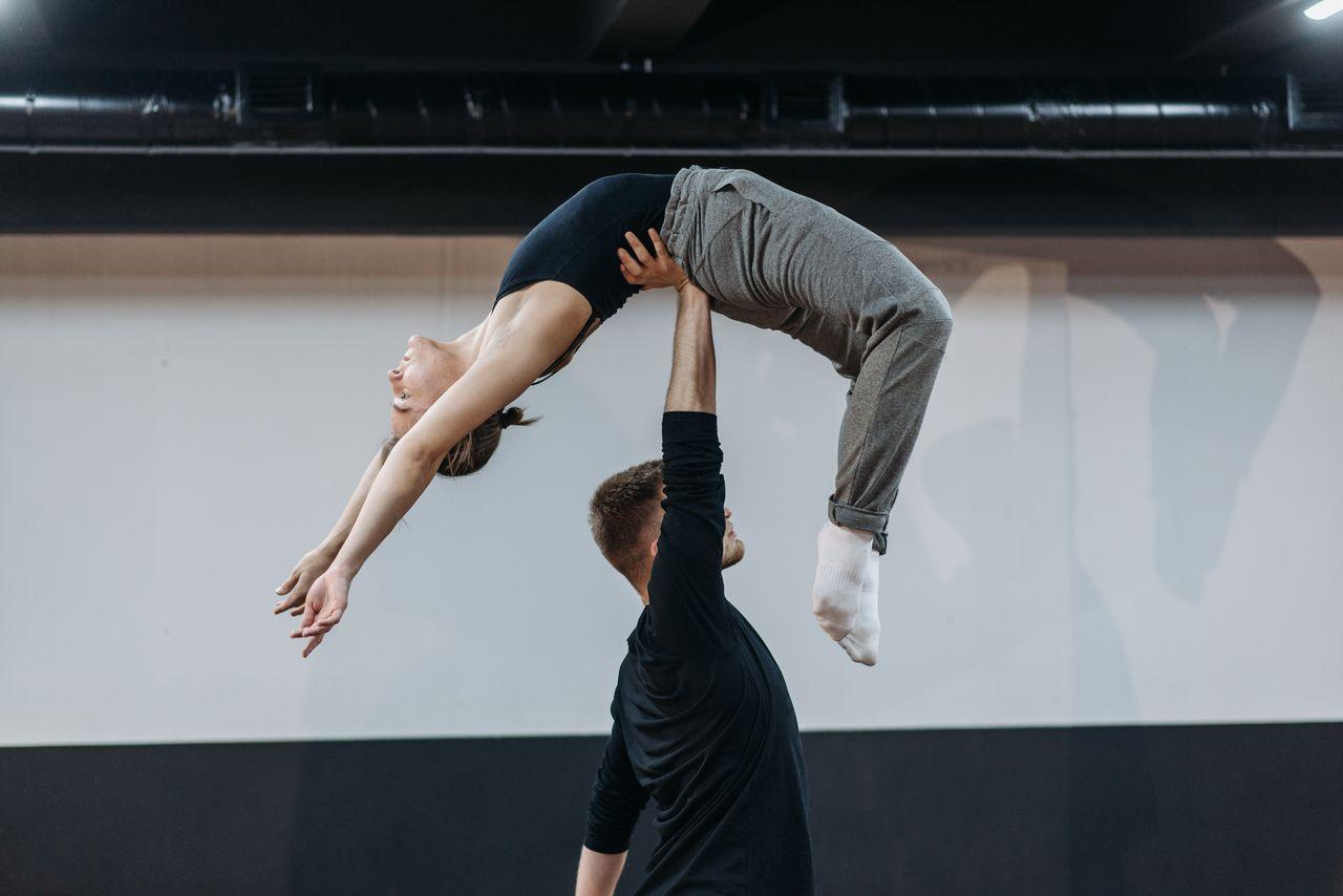 Two dancers performing an acrobatic lift in a studio, showcasing flexibility.