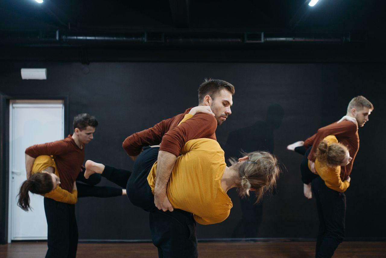 Dancers engaged in a passionate contemporary dance rehearsal in a studio setting.
