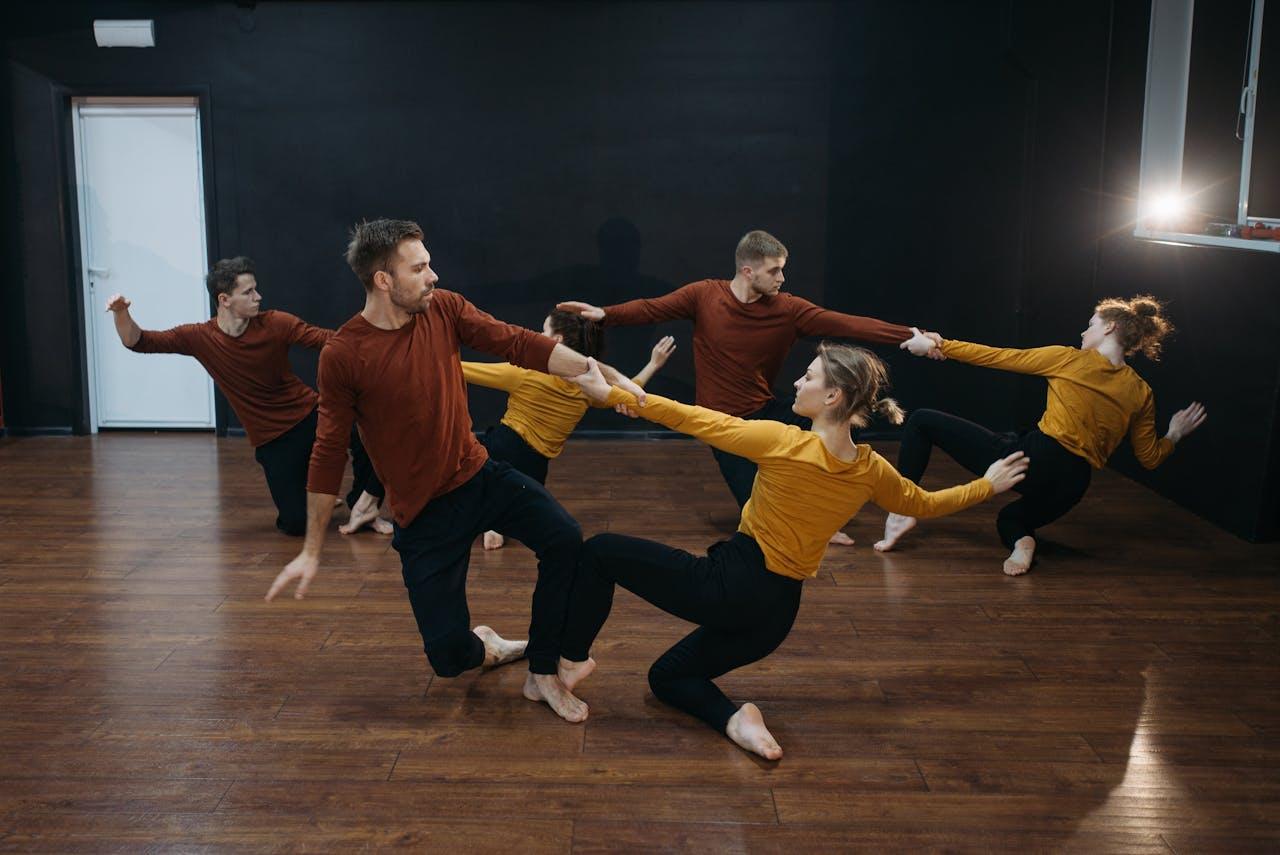 A group of contemporary dancers rehearsing with passion and flexibility in a studio setting.