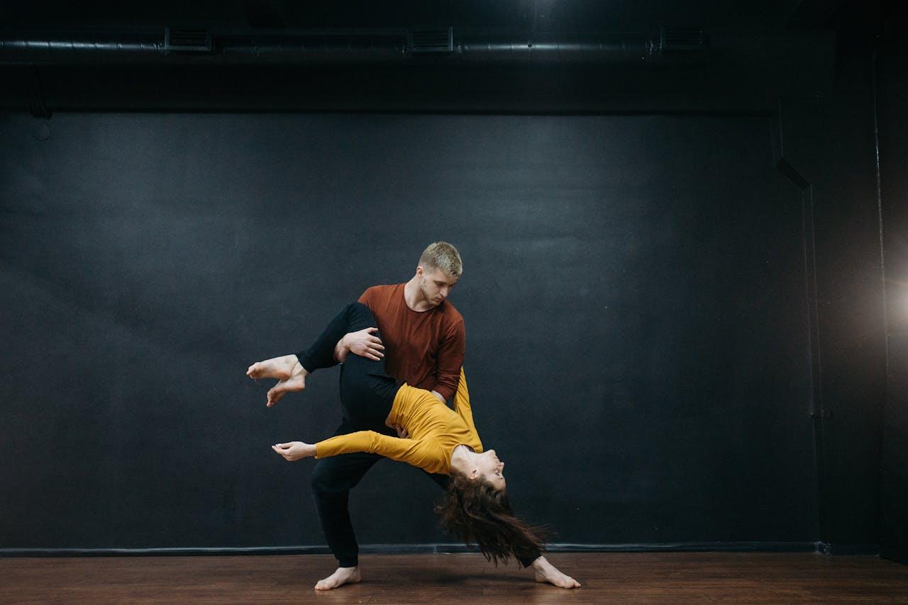A couple performing an expressive dance move in a studio setting.